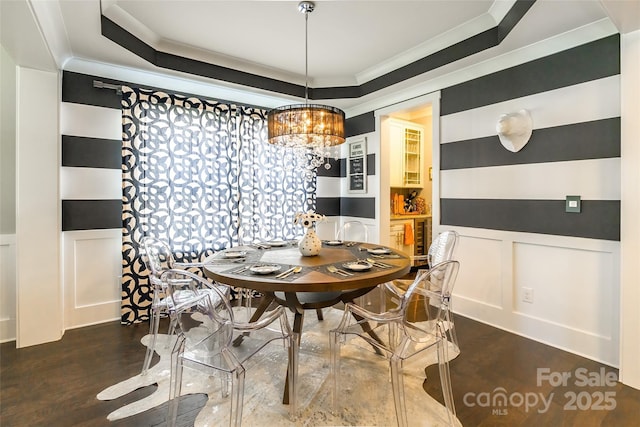dining room with ornamental molding, wood finished floors, a decorative wall, and a chandelier