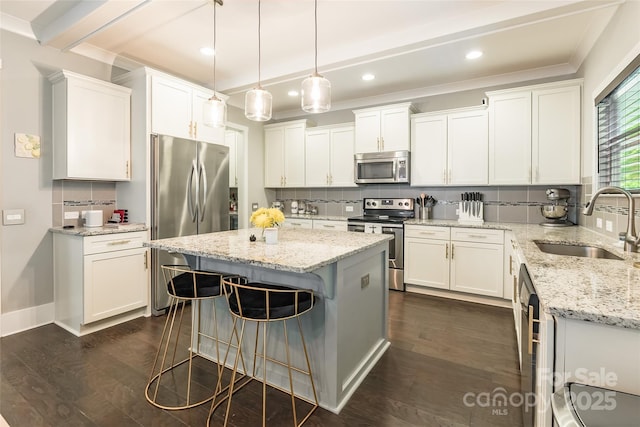 kitchen featuring decorative backsplash, appliances with stainless steel finishes, a kitchen island, white cabinets, and a sink