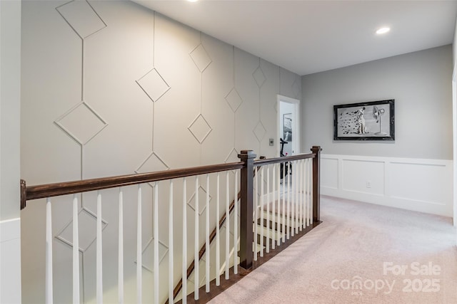 corridor featuring an upstairs landing, carpet, a decorative wall, and recessed lighting
