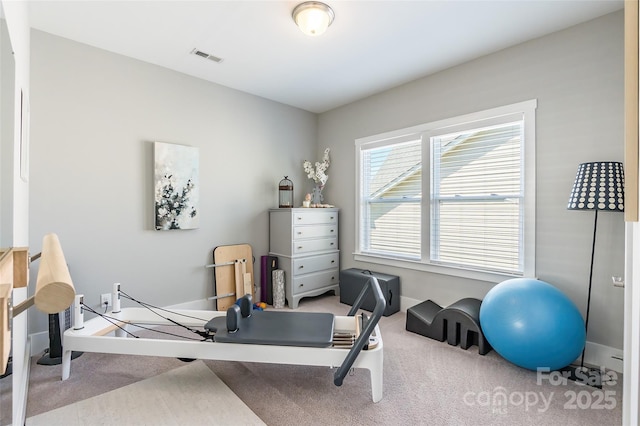 exercise area with visible vents, carpet, and baseboards
