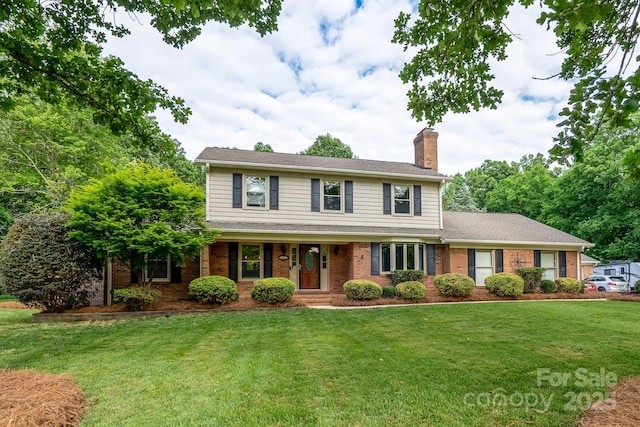 view of front of house featuring a chimney, a front lawn, and brick siding