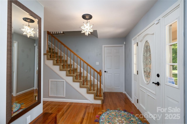 foyer featuring stairs, wood finished floors, and baseboards