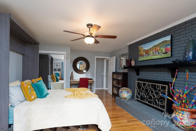 bedroom featuring light wood finished floors, a fireplace, a ceiling fan, baseboards, and a closet