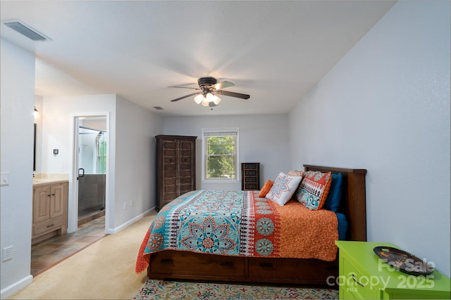 bedroom featuring light carpet, baseboards, a ceiling fan, and ensuite bath