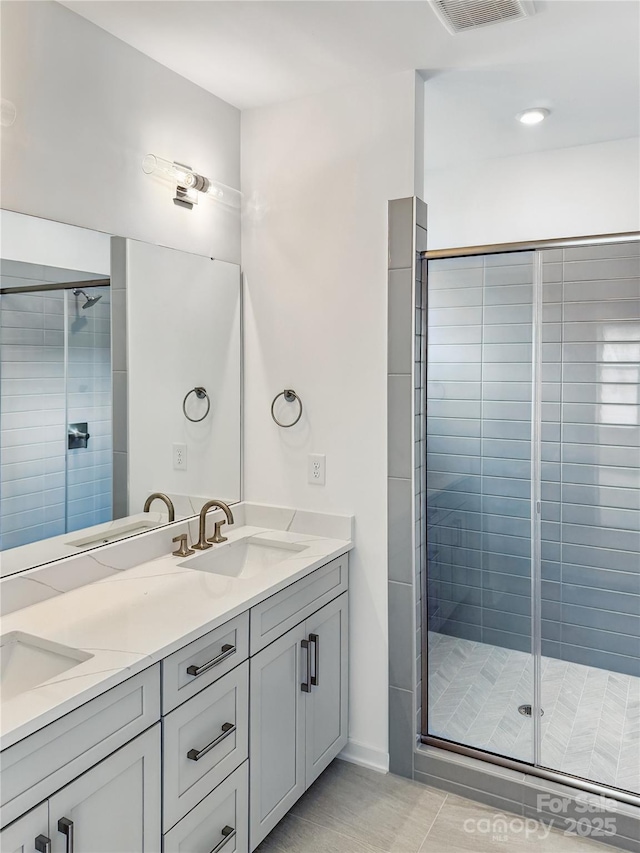 bathroom with visible vents, a shower stall, double vanity, and a sink