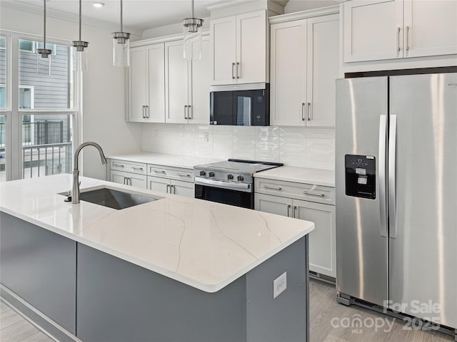 kitchen featuring tasteful backsplash, a sink, appliances with stainless steel finishes, light wood-type flooring, and an island with sink