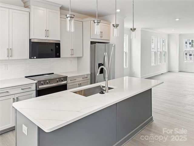 kitchen with recessed lighting, a sink, decorative backsplash, light wood-style floors, and appliances with stainless steel finishes