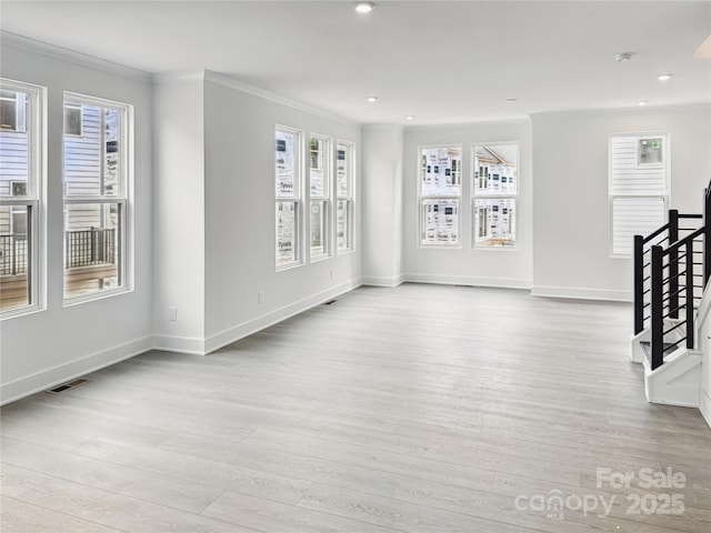 interior space with wood finished floors, visible vents, a healthy amount of sunlight, and ornamental molding