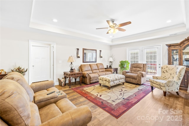 living room with ceiling fan, wood finished floors, a tray ceiling, and recessed lighting