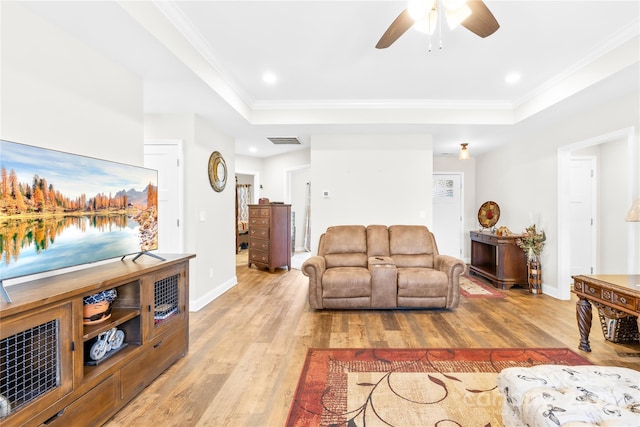 living area featuring ceiling fan, light wood finished floors, visible vents, and a raised ceiling