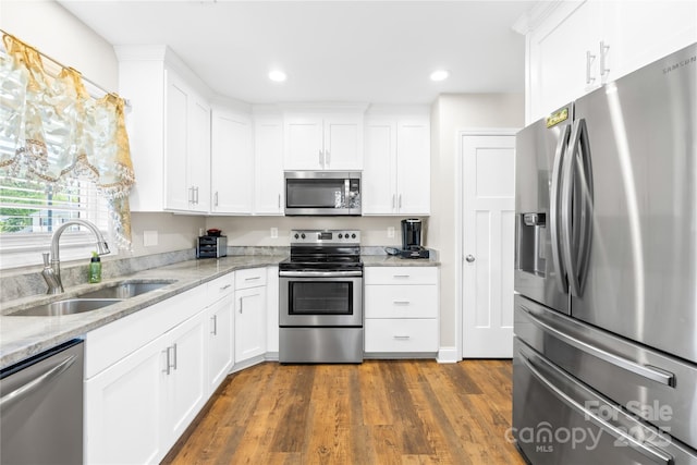 kitchen with white cabinets, dark wood-style floors, stainless steel appliances, and a sink