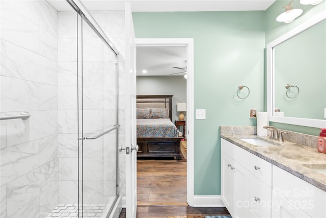 full bath with wood finished floors, a sink, a stall shower, ensuite bathroom, and double vanity