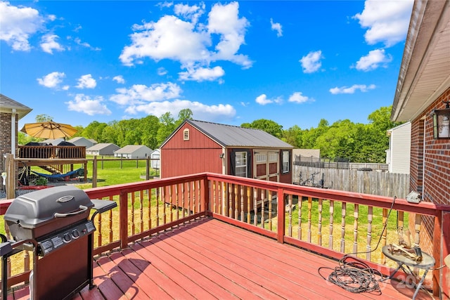 wooden terrace with an outdoor structure, a grill, fence, and a yard