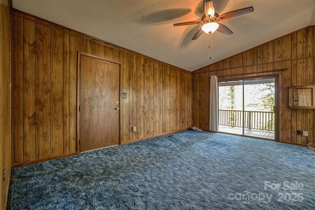 605 Hennessee St, Morganton, NC 28655 - carpeted empty room with wood walls, vaulted ceiling, a ceiling fan, and a textured ceiling
