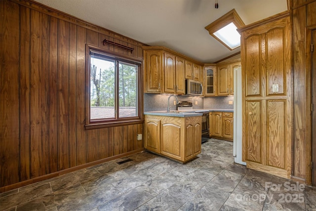 605 Hennessee St, Morganton, NC 28655 - kitchen with stainless steel microwave, range with electric cooktop, a peninsula, wooden walls, and brown cabinetry