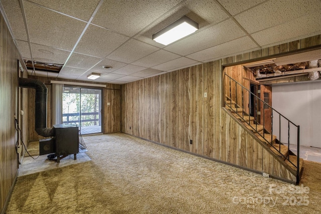 605 Hennessee St, Morganton, NC 28655 - below grade area featuring a wood stove, a paneled ceiling, wooden walls, stairs, and carpet