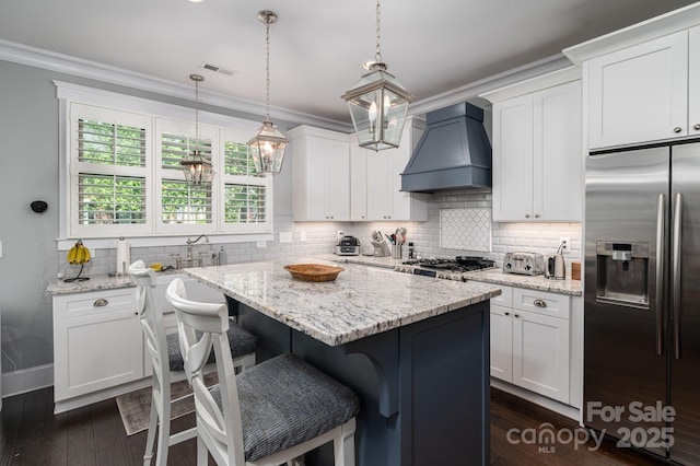 kitchen with white cabinetry, stainless steel fridge with ice dispenser, custom exhaust hood, and visible vents