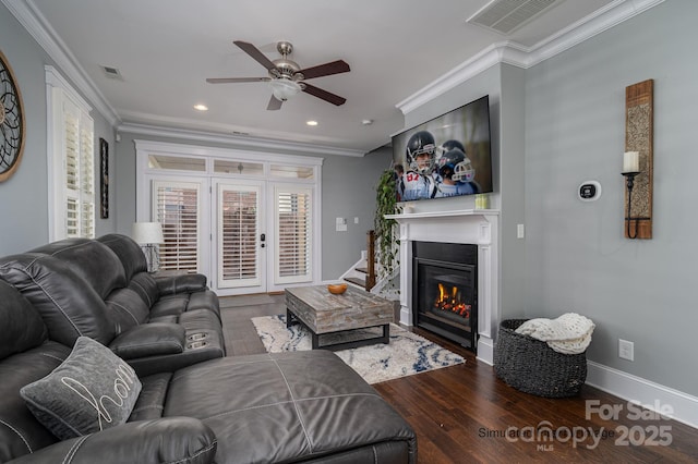 living area featuring wood finished floors, visible vents, crown molding, and a ceiling fan