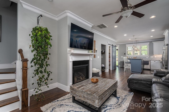 living room with stairway, a barn door, ceiling fan, baseboards, and visible vents