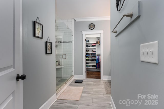 bathroom featuring a spacious closet, baseboards, and a stall shower