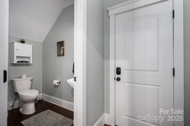 half bathroom featuring wood finished floors, baseboards, vaulted ceiling, and toilet