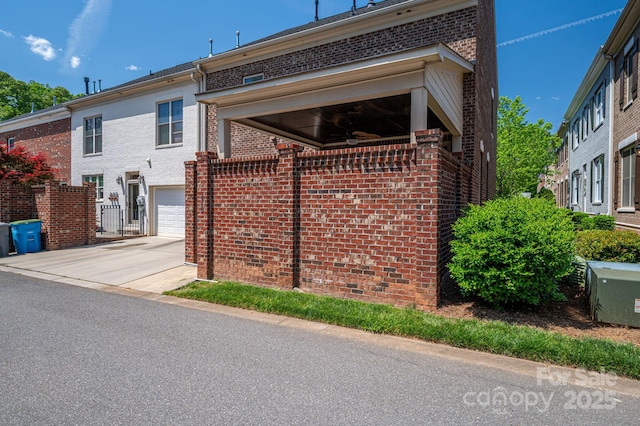 view of side of property featuring an attached garage, brick siding, and driveway