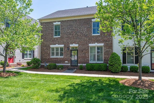 view of front facade with brick siding and a front yard