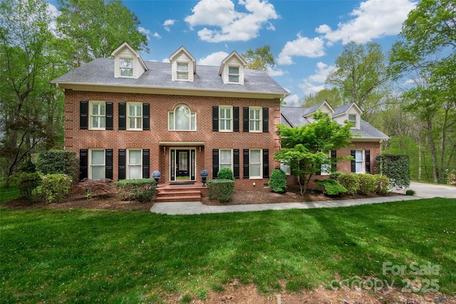 colonial house featuring brick siding and a front yard