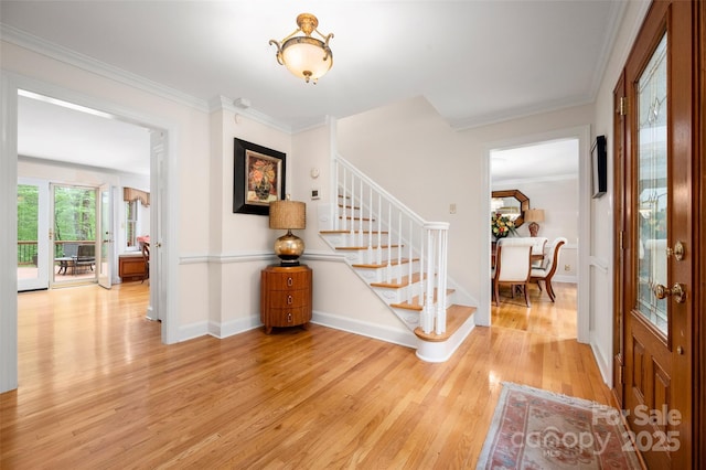foyer with light wood-type flooring, stairs, baseboards, and crown molding