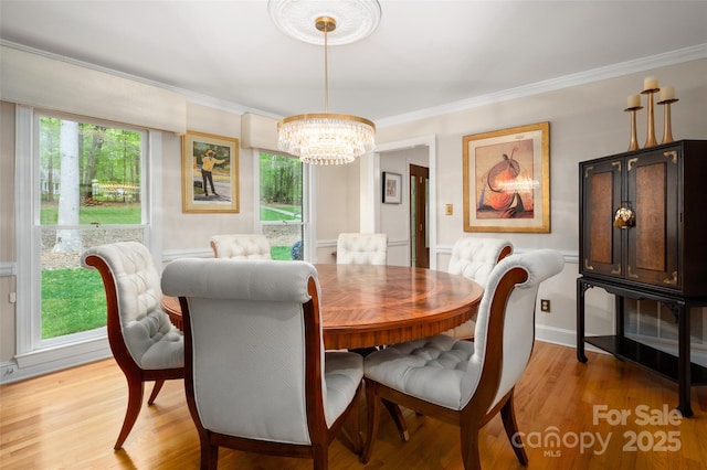 dining space featuring a chandelier, ornamental molding, and light wood finished floors