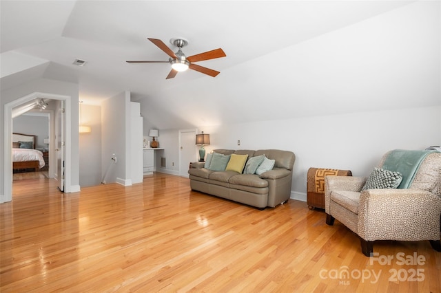 living room featuring a ceiling fan, vaulted ceiling, light wood-style floors, and baseboards