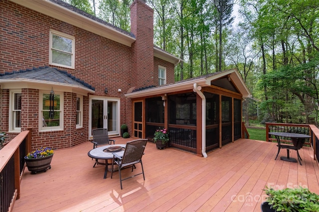 deck with a sunroom, an outdoor fire pit, and french doors