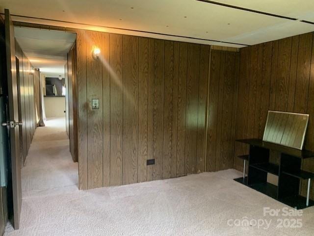 unfurnished living room featuring wooden walls and carpet