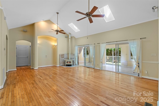 80 Ivy Cove Rd, Fairview, NC 28730 - unfurnished living room with high vaulted ceiling, a skylight, ceiling fan, arched walkways, and a wood stove