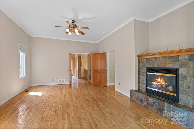 80 Ivy Cove Rd, Fairview, NC 28730 - unfurnished living room featuring crown molding, light wood-style flooring, ceiling fan, a tiled fireplace, and baseboards