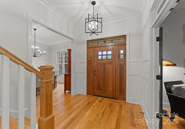 entryway featuring an inviting chandelier, plenty of natural light, light wood finished floors, and stairway