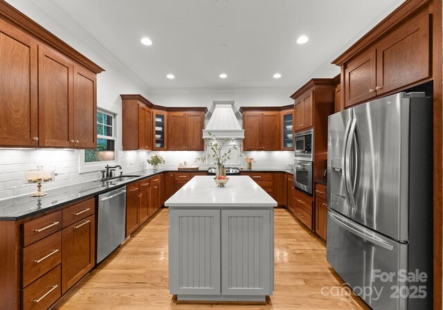 kitchen with decorative backsplash, custom exhaust hood, a center island, a sink, and appliances with stainless steel finishes