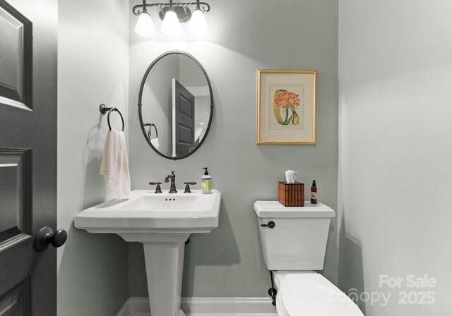 bathroom featuring baseboards, a sink, and toilet