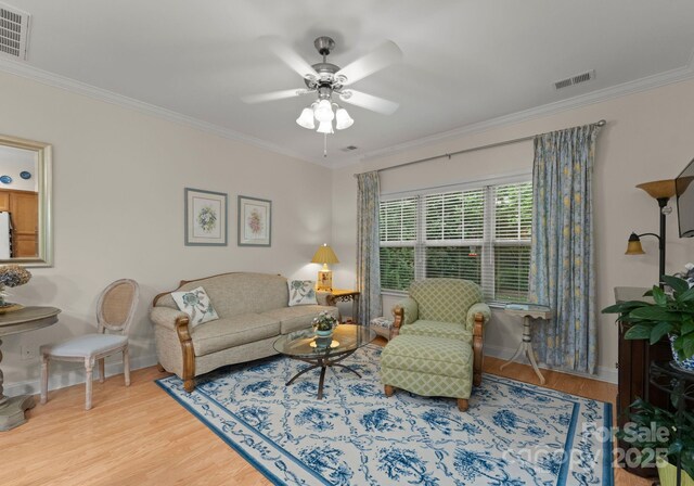 living area with visible vents, crown molding, and wood finished floors