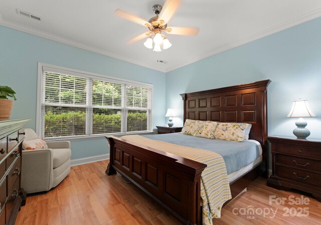 bedroom with crown molding, visible vents, and light wood finished floors