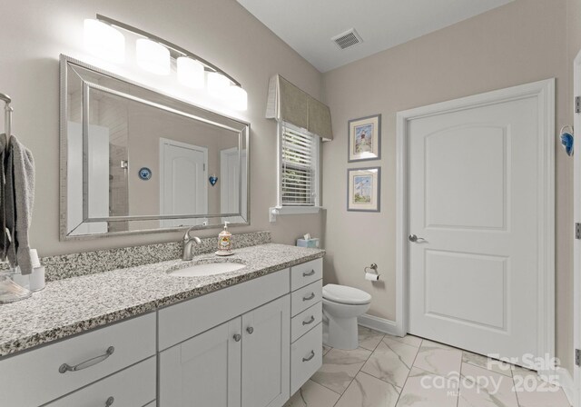 bathroom featuring vanity, toilet, marble finish floor, a shower, and visible vents