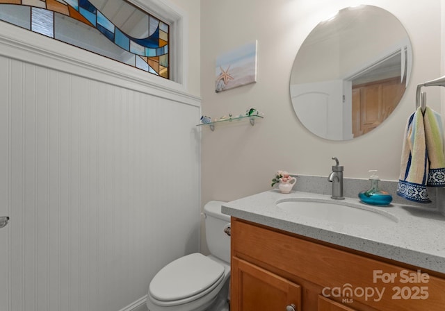 half bath featuring vanity and toilet