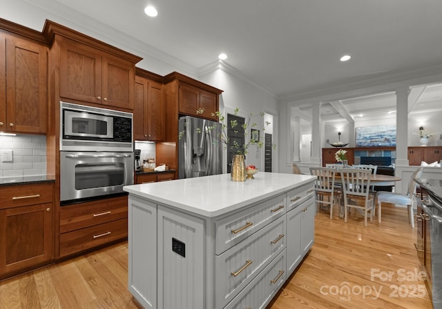 kitchen with a kitchen island, tasteful backsplash, ornamental molding, stainless steel appliances, and light wood-style flooring