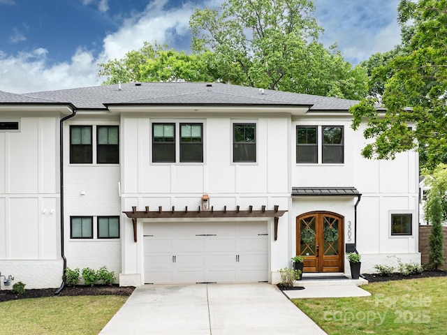 modern farmhouse style home with concrete driveway, board and batten siding, a standing seam roof, a front yard, and a garage