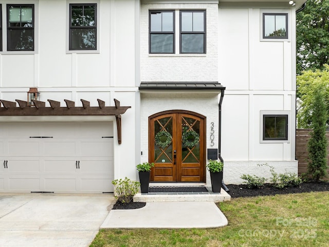 view of front of property with a garage, concrete driveway, metal roof, stucco siding, and a standing seam roof