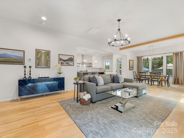 living room featuring visible vents, baseboards, recessed lighting, a notable chandelier, and wood finished floors