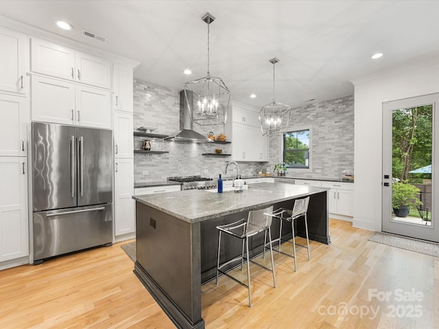 kitchen with wall chimney range hood, tasteful backsplash, open shelves, high quality fridge, and visible vents