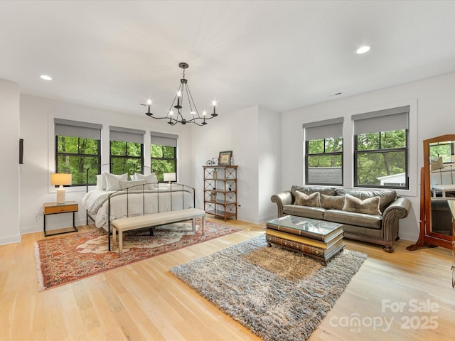 bedroom featuring light wood finished floors, a notable chandelier, and multiple windows