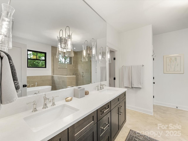 bathroom with baseboards, a sink, double vanity, and a stall shower