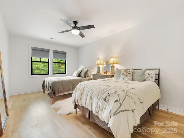bedroom featuring ceiling fan, baseboards, and light wood finished floors